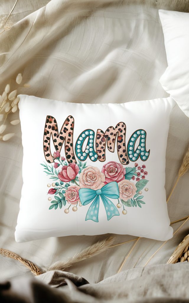 A decorative pillow with a bold "Mama" design in leopard print, surrounded by roses and a soft teal bow.